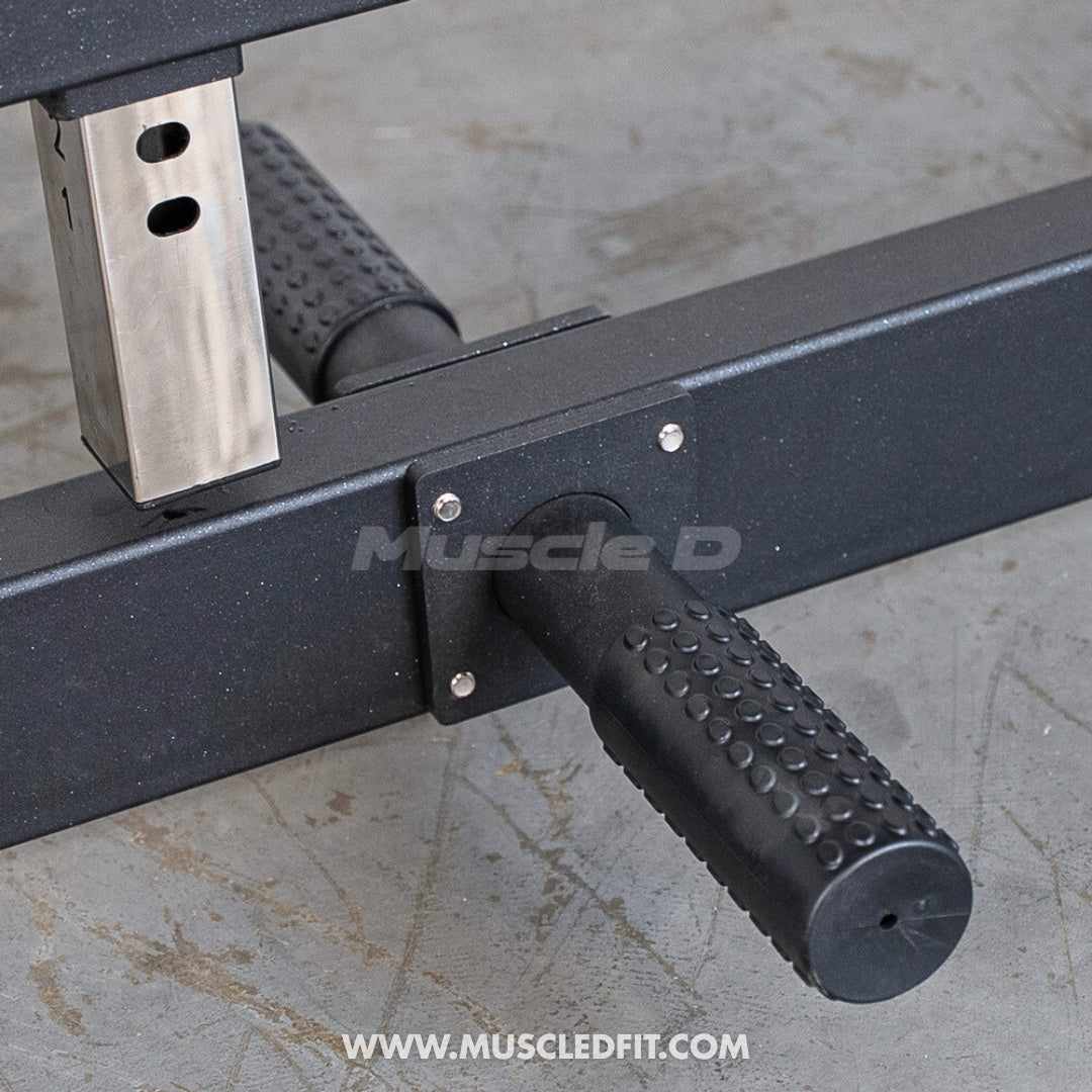 Close-up of a black textured footrest and a silver adjustment bar on a fitness machine.