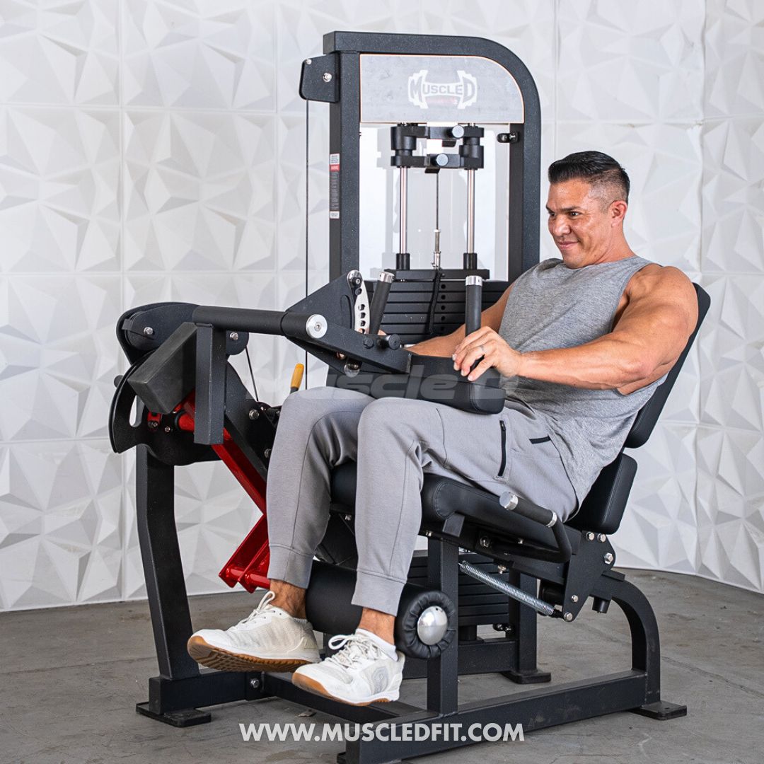 Man using a black and red leg extension/curl machine with weight stack.