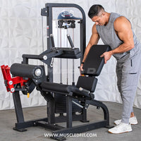 Thumbnail for Man adjusting the seat of a black and red leg extension/curl combo machine with a weight stack.