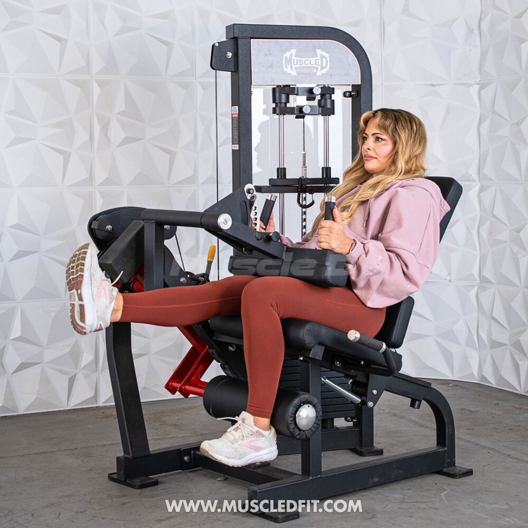 Woman doing leg extension on a black and red Muscle D combo machine.