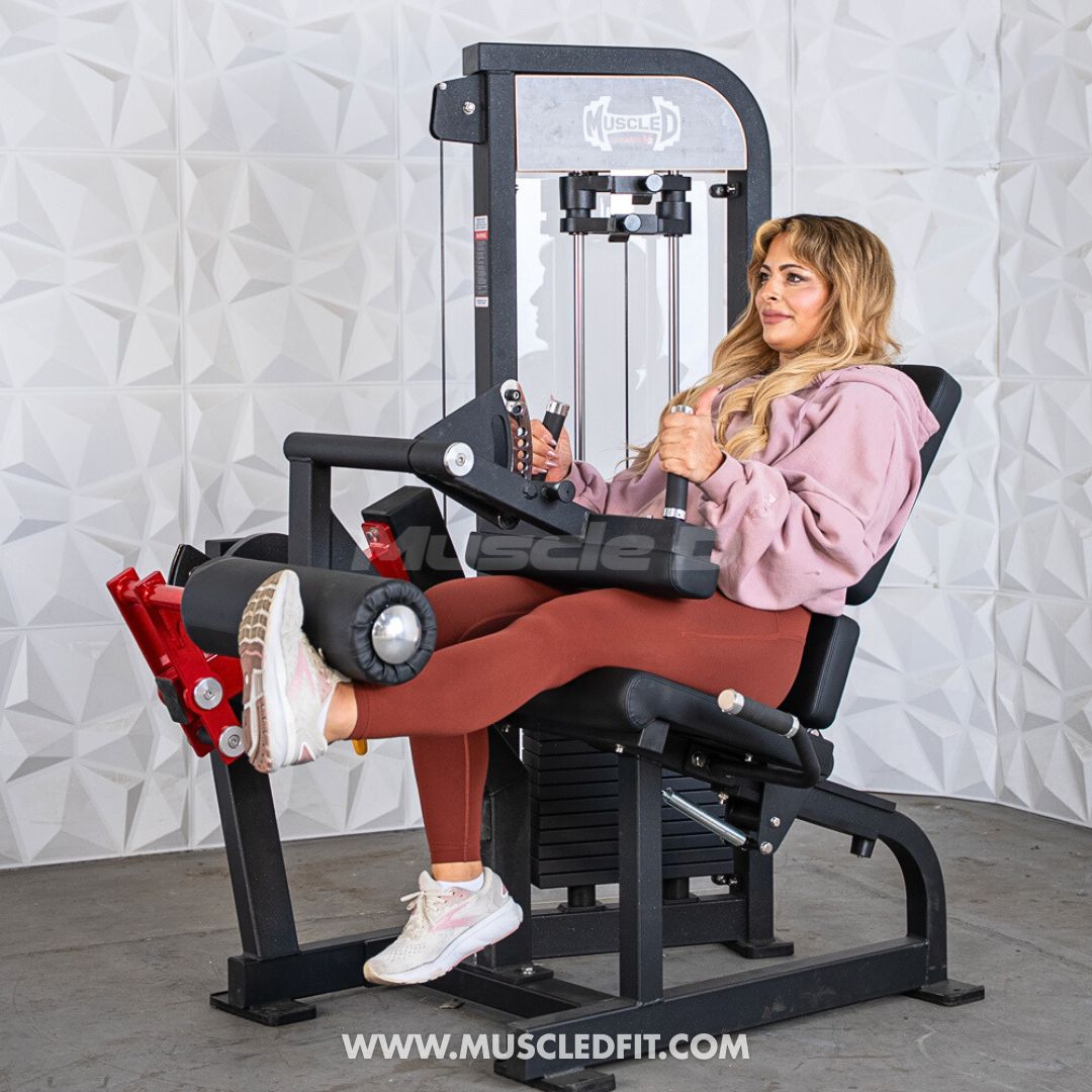 Woman using a black and red leg extension/curl machine with a weight stack.