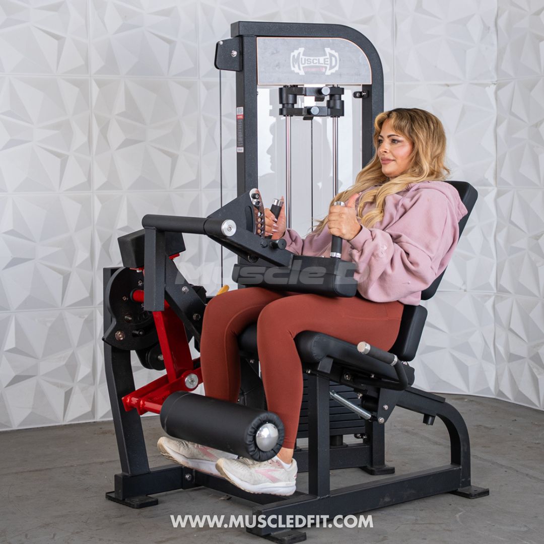 Woman using a black and red selectorized leg extension/seated leg curl combo machine.