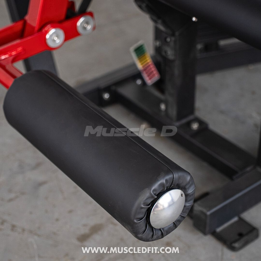 Close-up of the black padded roller on a red and black leg extension/curl machine.