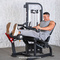 Thumbnail for Man using a black selectorized leg extension/curl machine with red accents against a white textured wall.