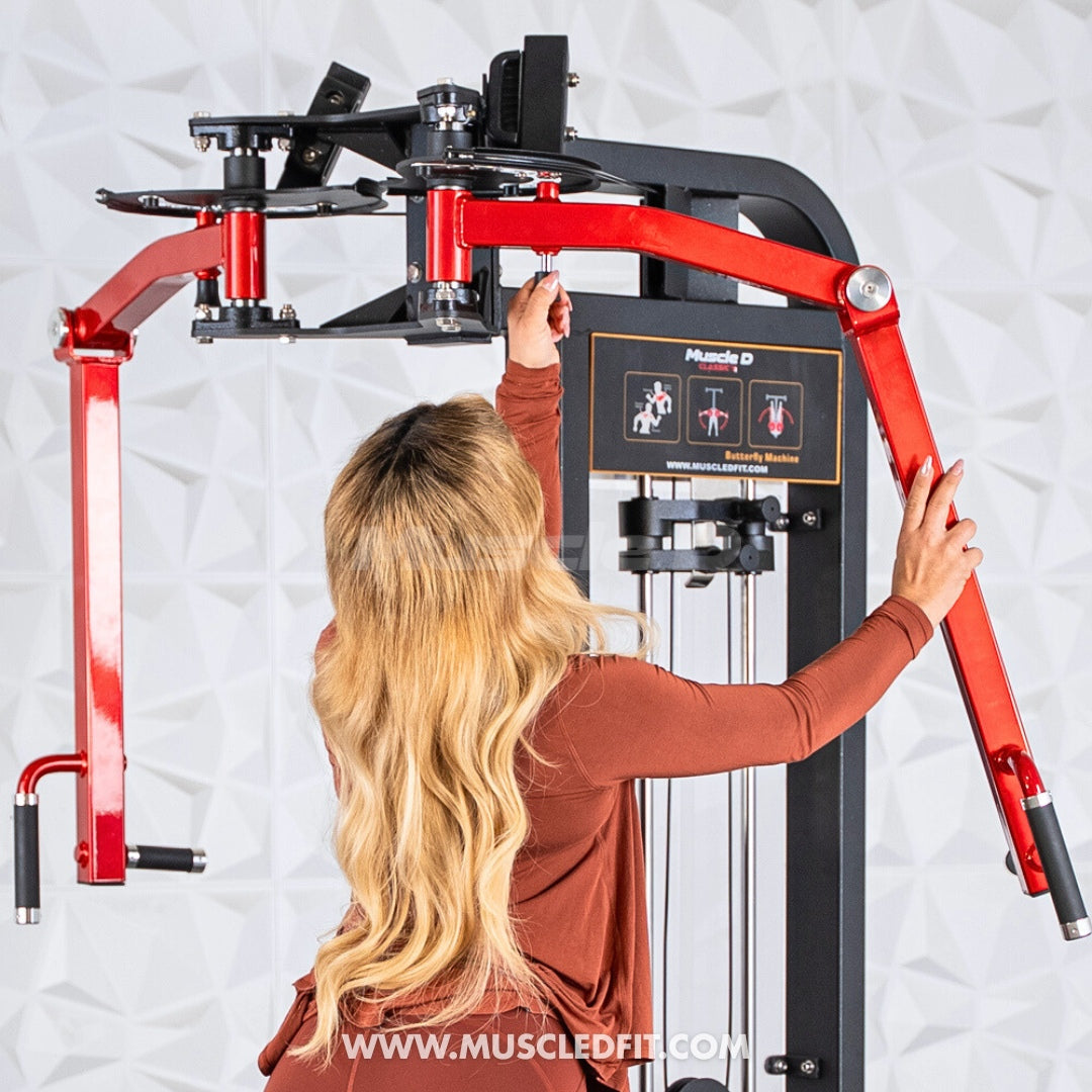 Woman adjusting the red arms of a black and red pec/rear delt combo machine.