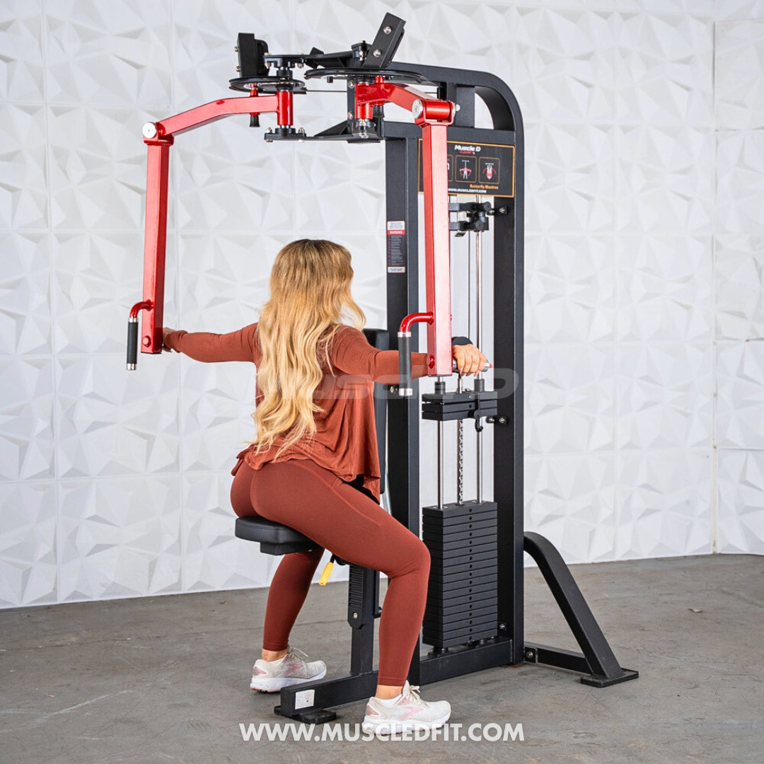 Woman using a black and red pec/rear delt combo machine with a weight stack.