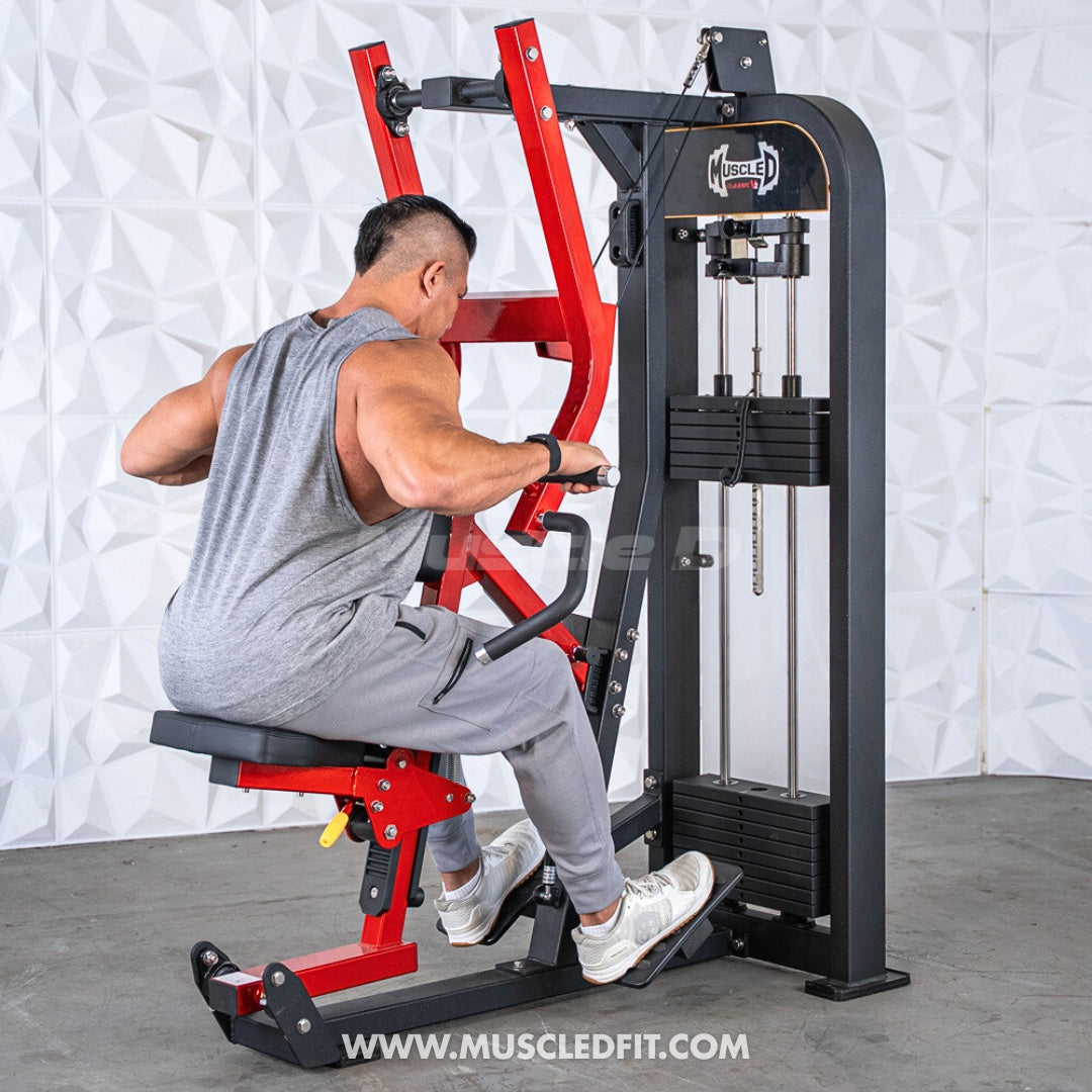 Man in grey tank top using a red and black seated row machine with weight stacks.