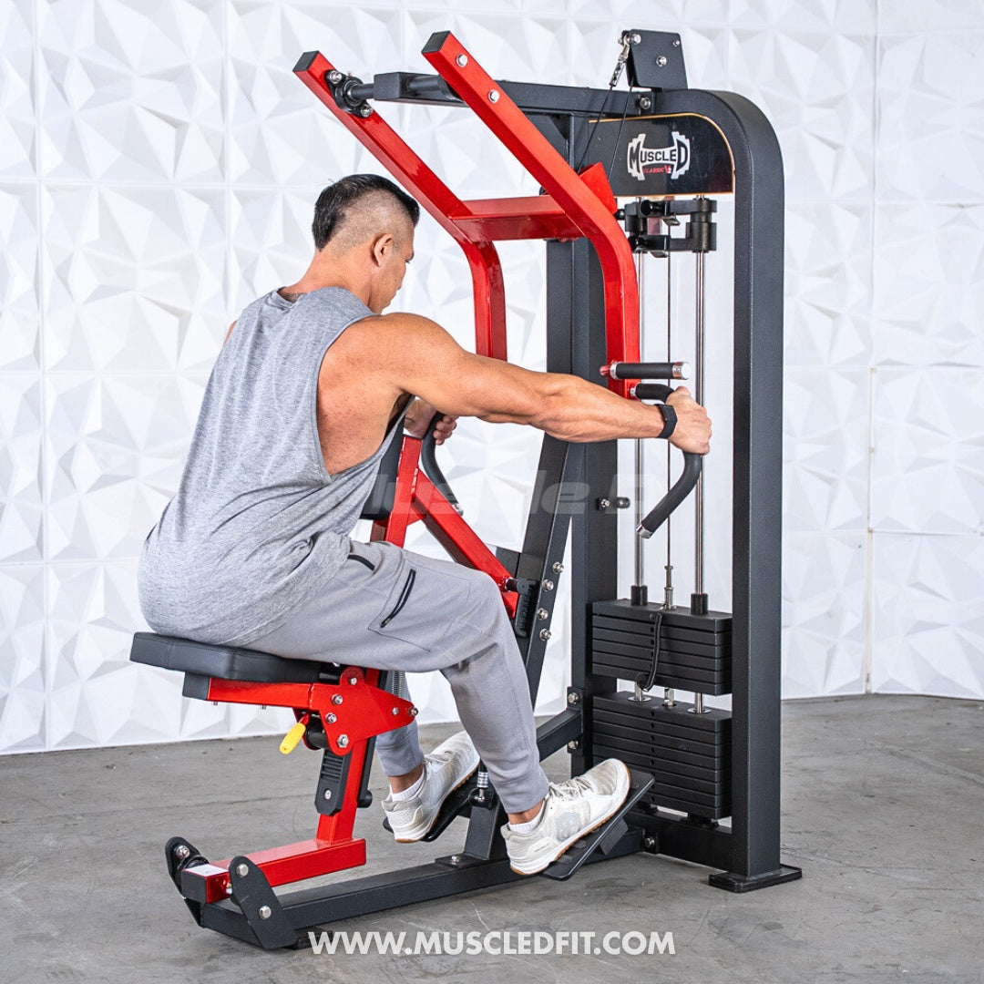 Man in a gray tank top using a red and black seated row machine with a weight stack.