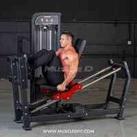 Thumbnail for Man in a tank top using a black and red selectorized leg press machine in a gym.