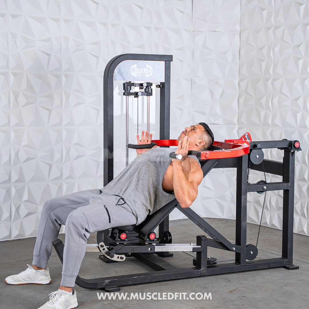 Man using a black and red multi-press chest and shoulder machine with a white textured wall background.