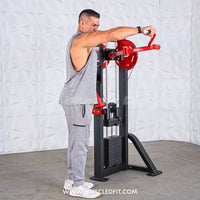 Thumbnail for Man in grey tank top using a black and red lateral raise machine with weight stack.