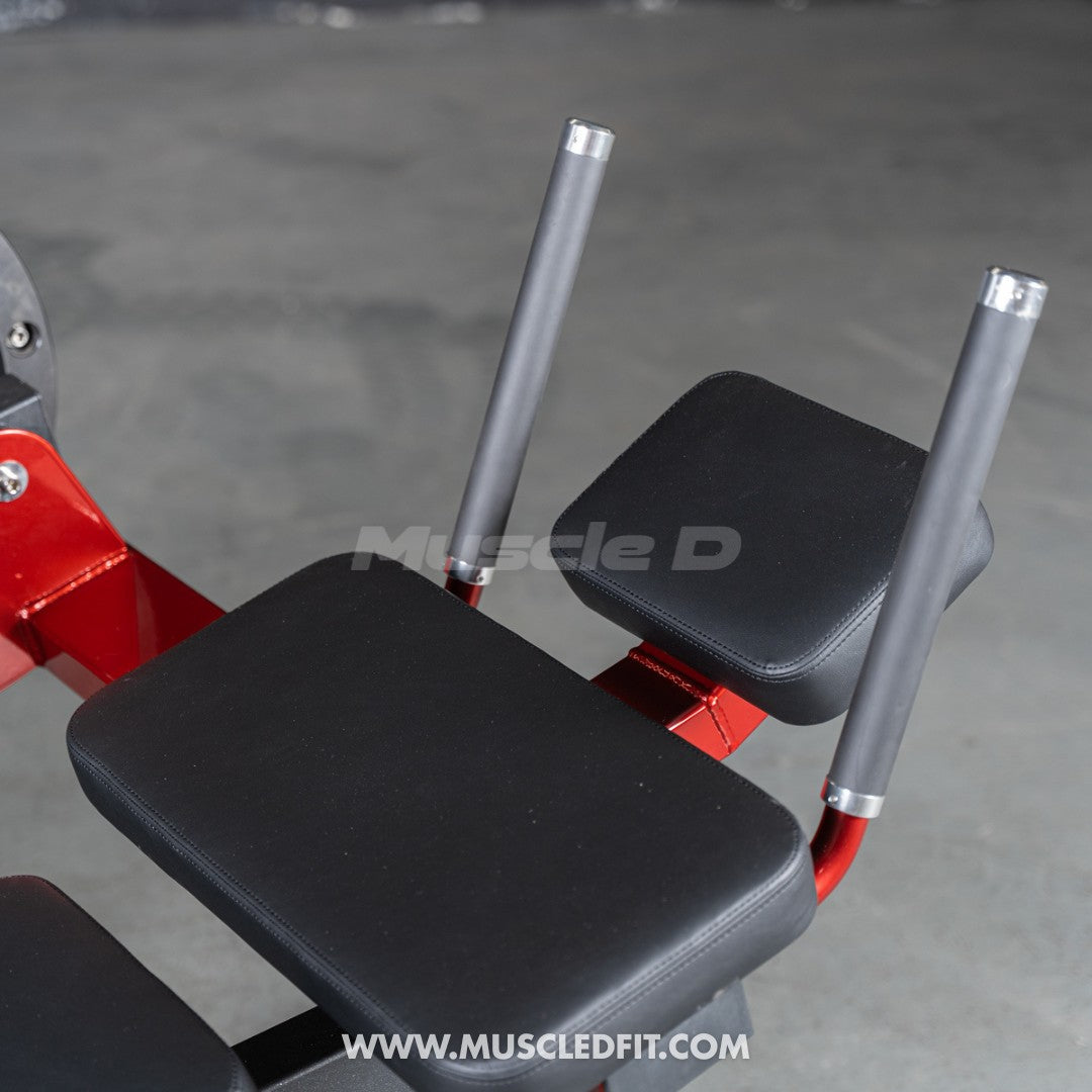 Close-up of black padded seats and gray handles on a red abdominal crunch machine.