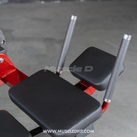 Thumbnail for Close-up of black padded seats and gray handles on a red abdominal crunch machine.