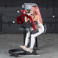 Thumbnail for Woman with pink hair using a red and black triceps extension machine in a gym.
