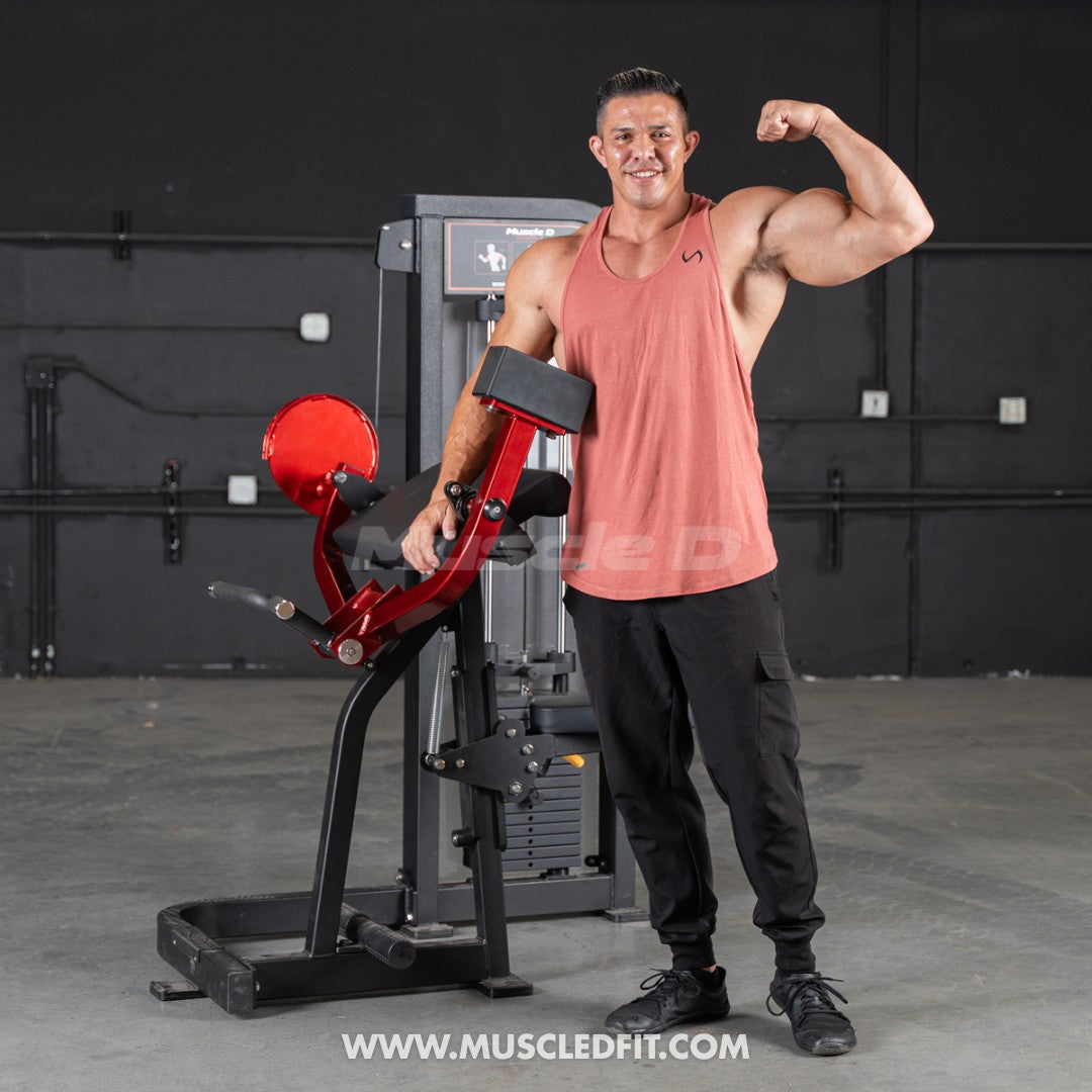 Man flexing bicep next to a red and black selectorized biceps curl machine with a weight stack.