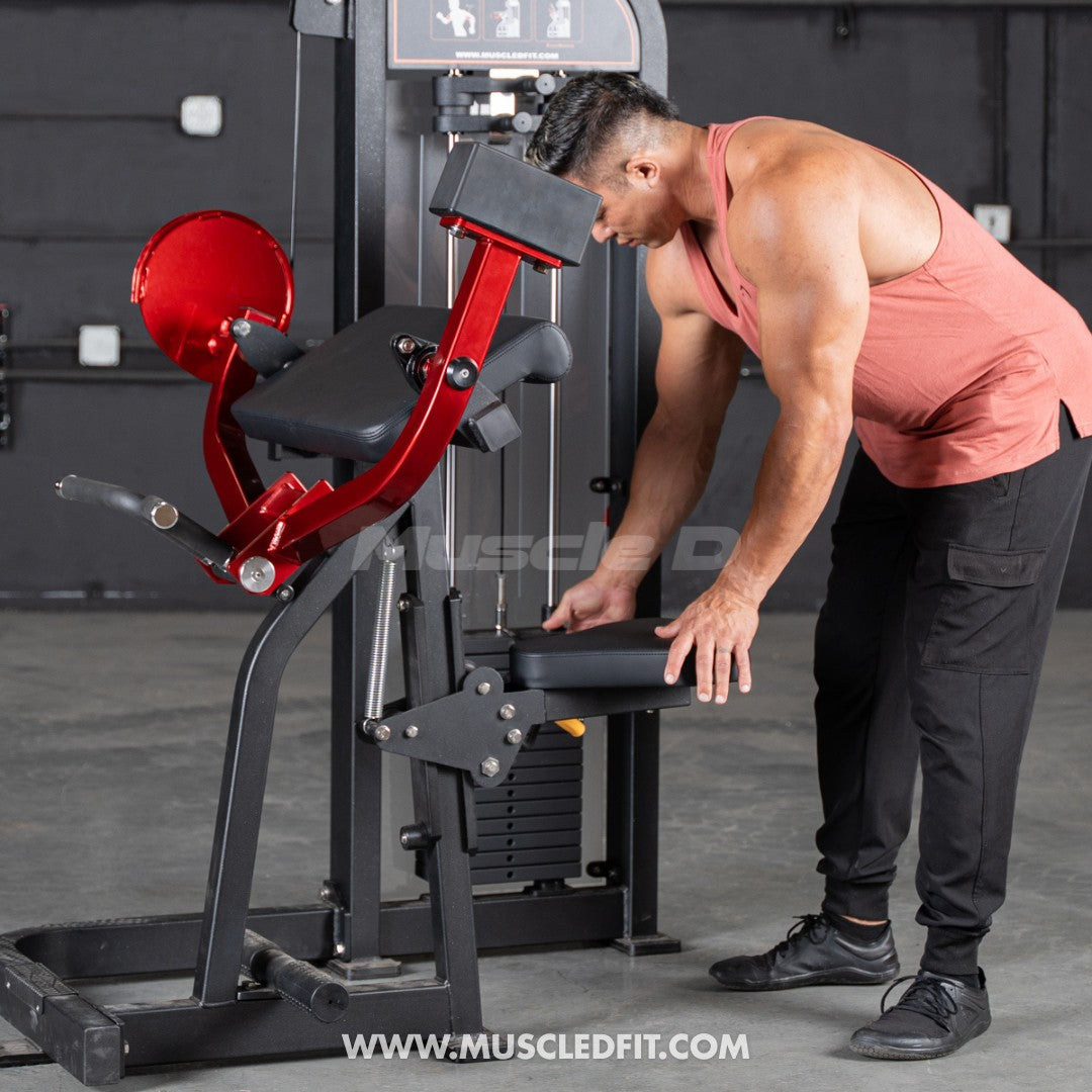 Man adjusting the seat of a red and black selectorized biceps curl machine with a weight stack.