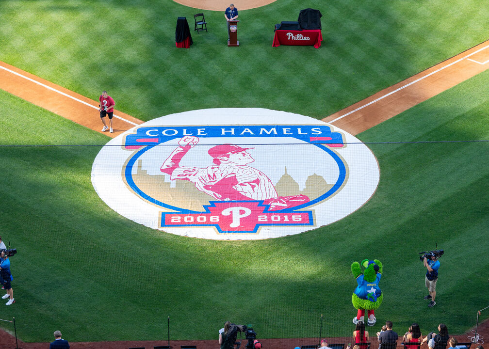 Round white rain spot cover printed with a Cole Hamels Phillies 2006-2015 graphic laid on a stadium baseball infield