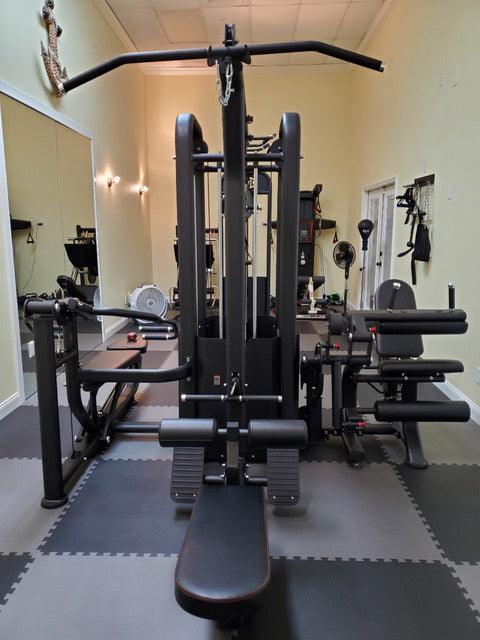 Black 5-stack compact multi-gym with lat pull, low row, bench press, and leg extension/curl stations.