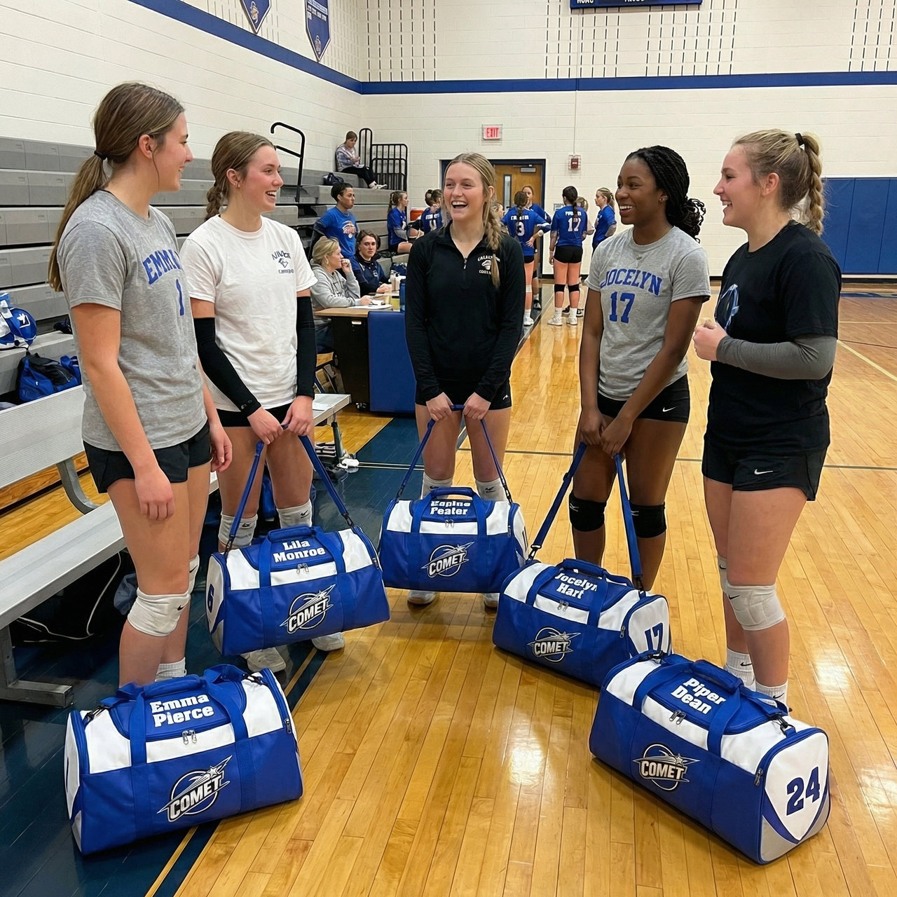Five smiling volleyball players with personalized blue and white duffle bags on a gym floor.