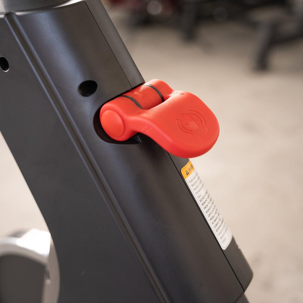 Close-up of a red adjustment knob on a black exercise bike frame.