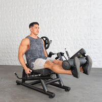 Thumbnail for Man performing a leg extension exercise on a black plate-loaded quad and hamstring machine.
