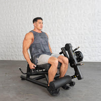 Thumbnail for Man seated on a black leg extension/curl machine, ready to exercise.