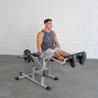 Thumbnail for Man using a silver and black plate-loaded leg extension/curl machine with a 25lb weight plate.
