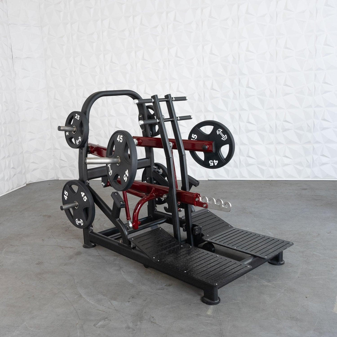 Black and red plate-loaded belt squat machine with 25lb and 45lb weight plates.