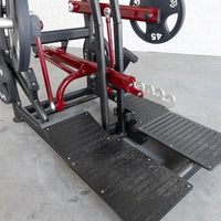 Thumbnail for Red and black plate-loaded belt squat machine with textured foot platforms and weight plates.