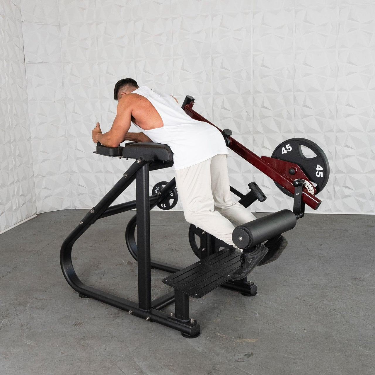 Man using a black and red plate-loaded reverse hyper machine with a 45lb weight plate.
