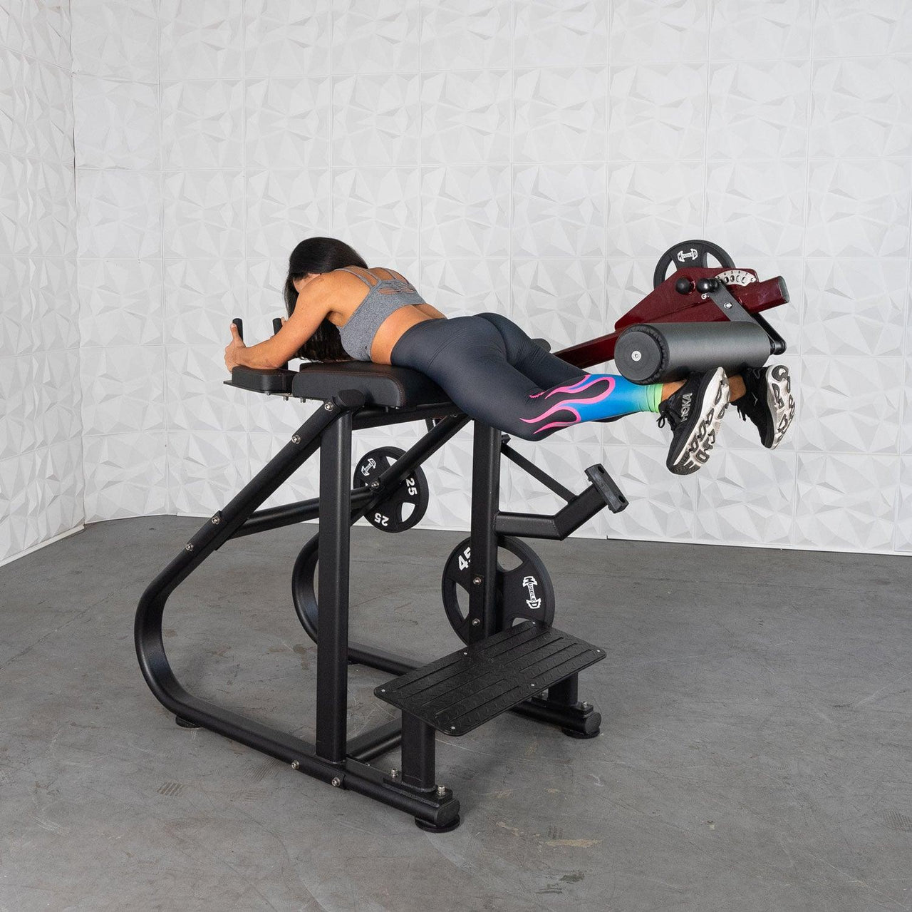Woman using a black and red reverse hyper extension machine with plate weights.