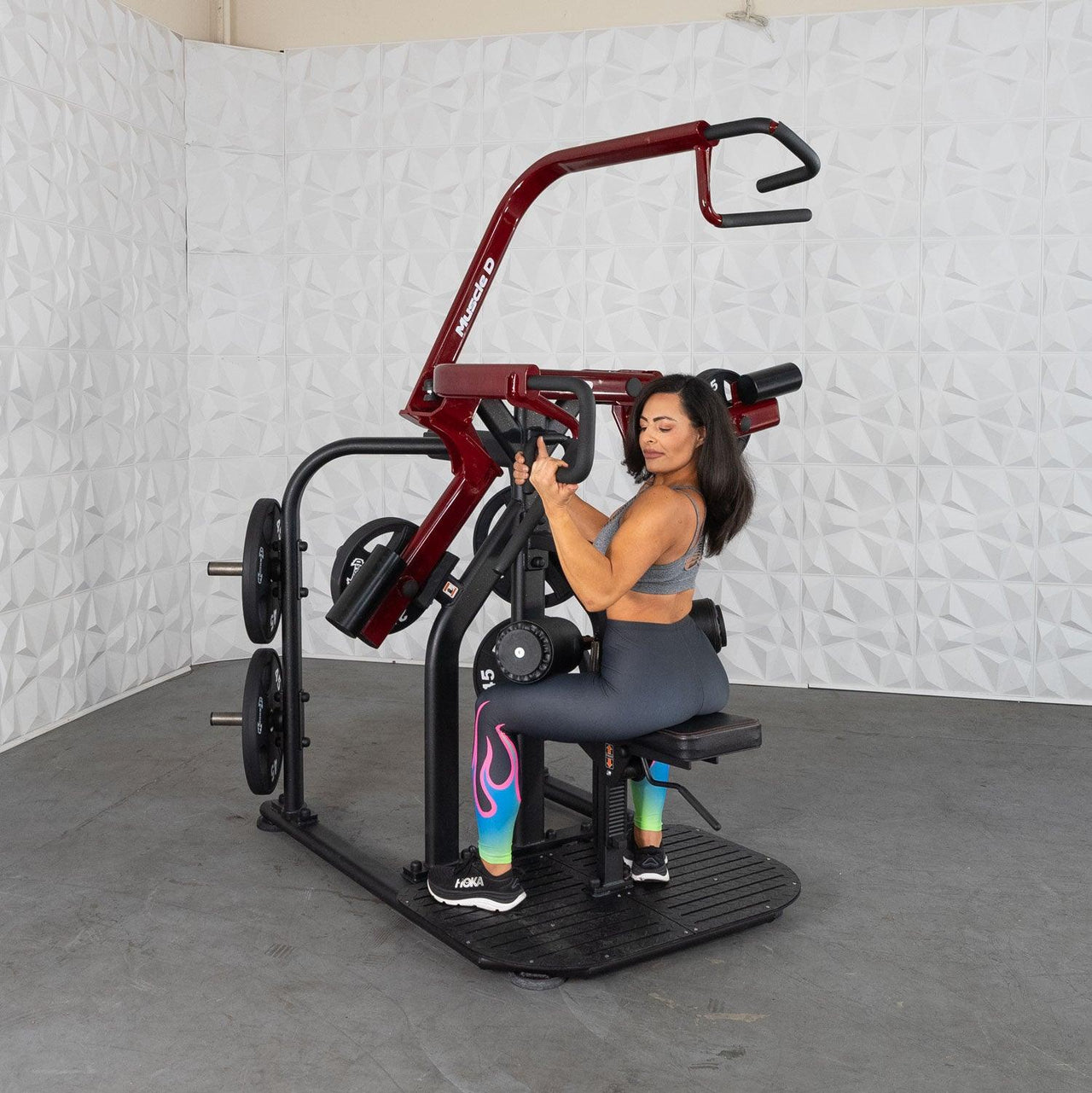 Woman using a red and black plate-loaded rotary lat pull-down machine.