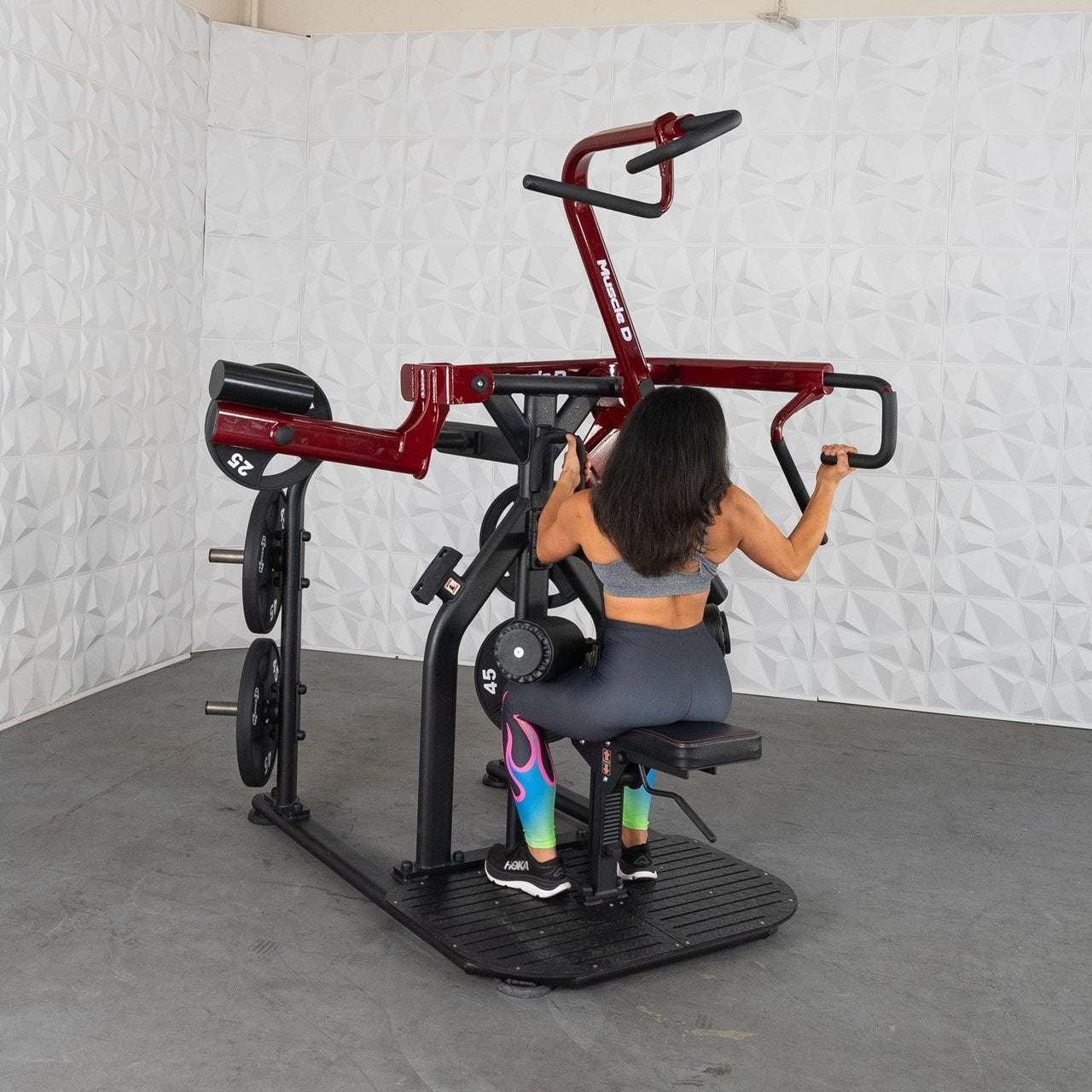 Woman using a red and black plate-loaded rotary lat pull-down machine.