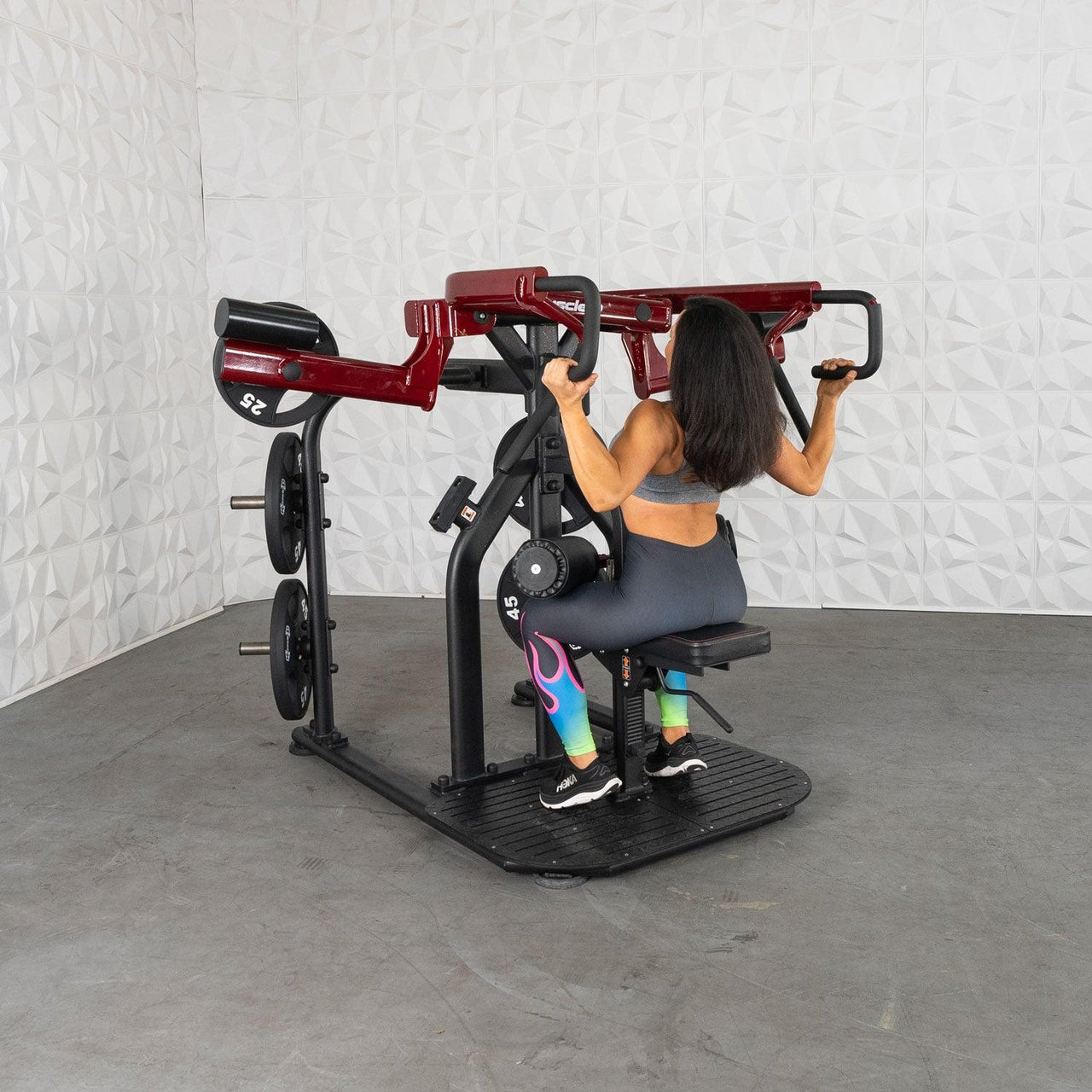 Woman using a red and black plate-loaded rotary lat pull-down machine.