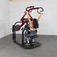 Thumbnail for Woman using a red and black plate-loaded lat pulldown machine with her arms extended upwards.
