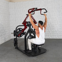 Thumbnail for Man in white tank top using a red and black rotary lat pull-down machine with 45lb plates.