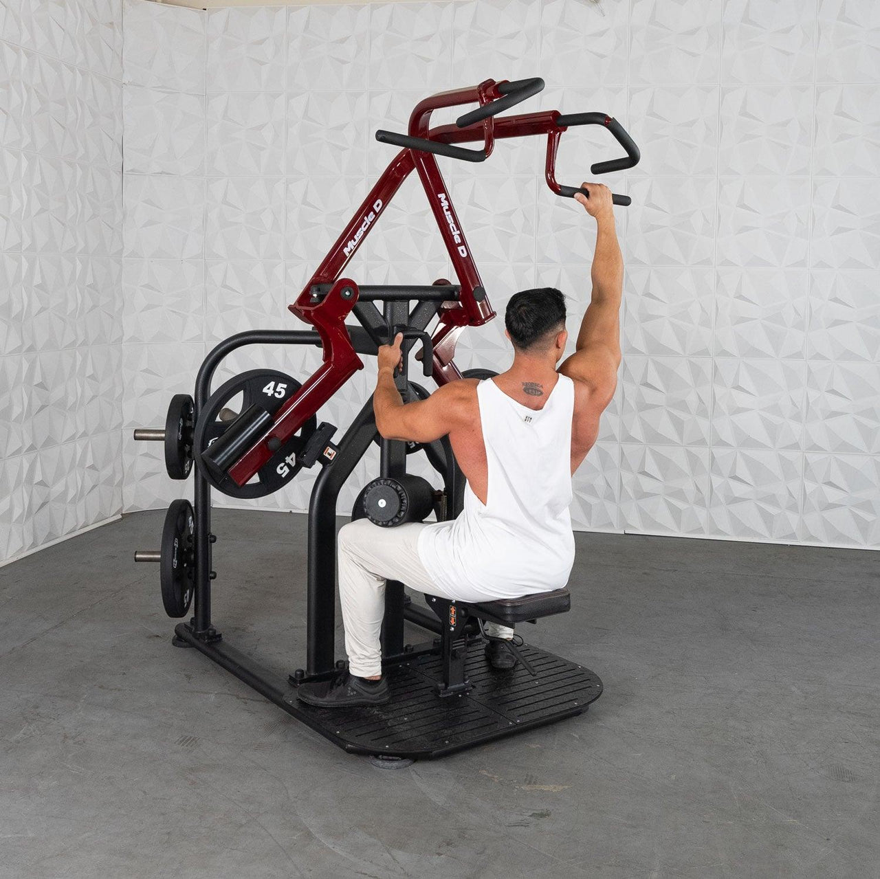 Man in white tank top using a red and black plate-loaded lat pulldown machine.