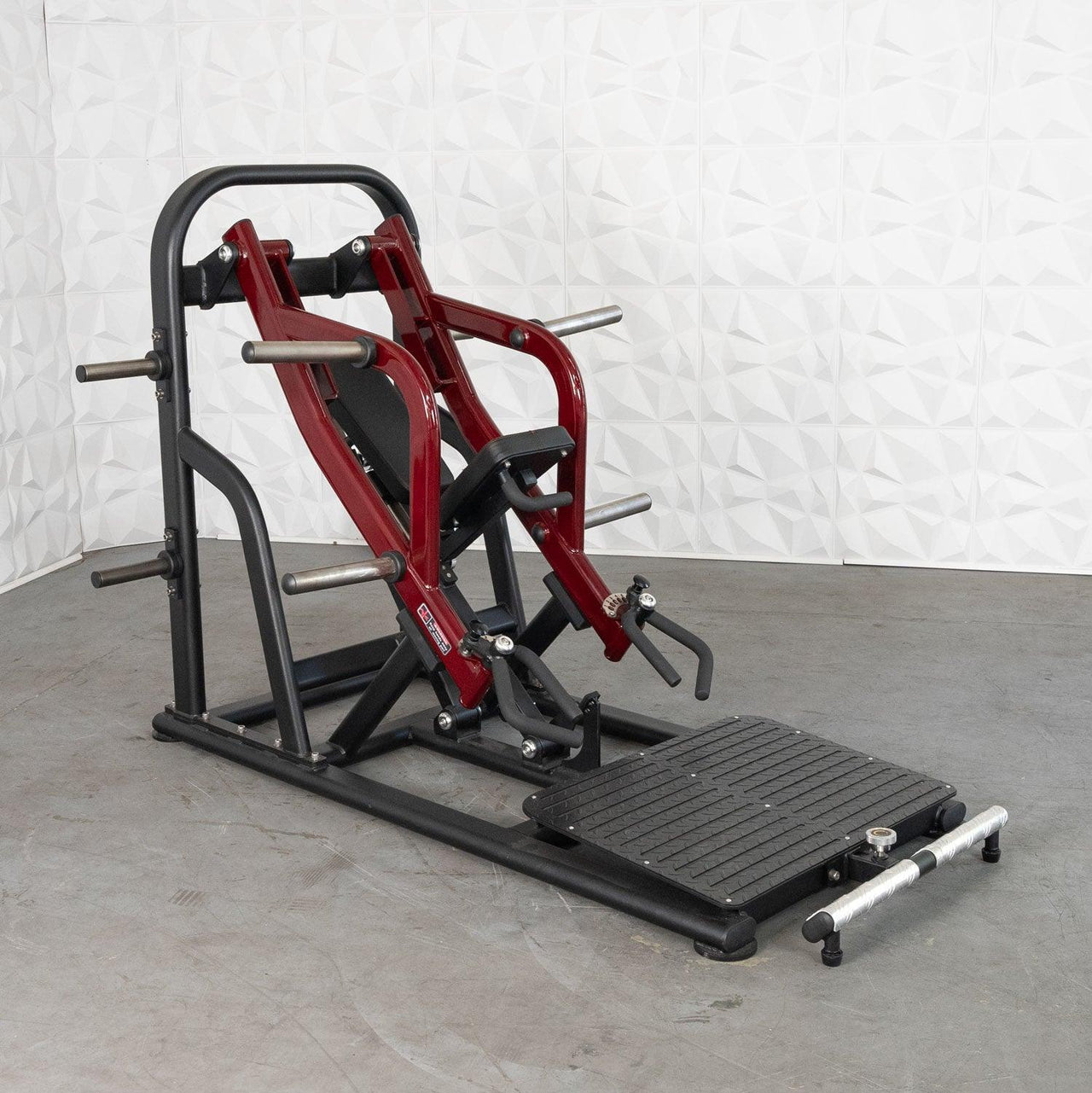 Red and black chest-supported plate-loaded rowing machine with a textured footplate.