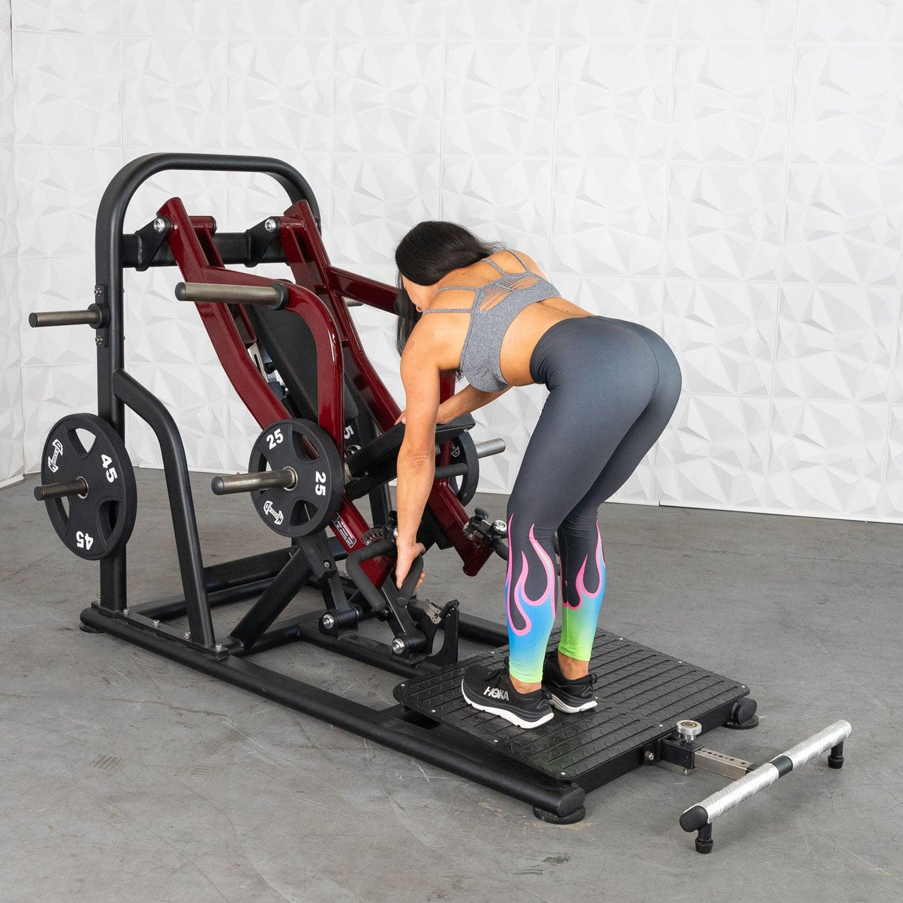 Woman adjusting a red and black chest-supported row machine with weight plates.