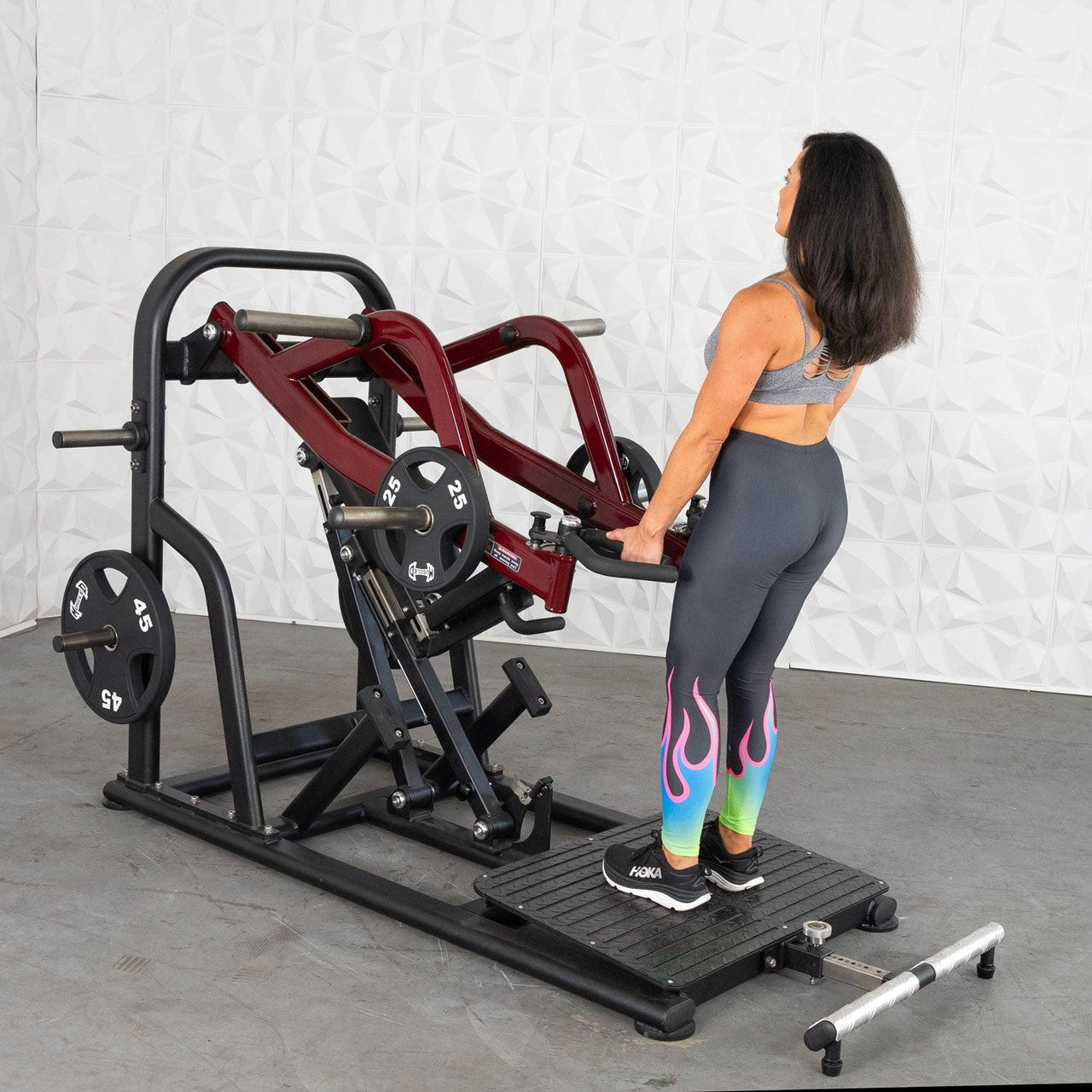 Woman using a red and black plate-loaded chest-supported row machine with 25lb and 45lb weights.