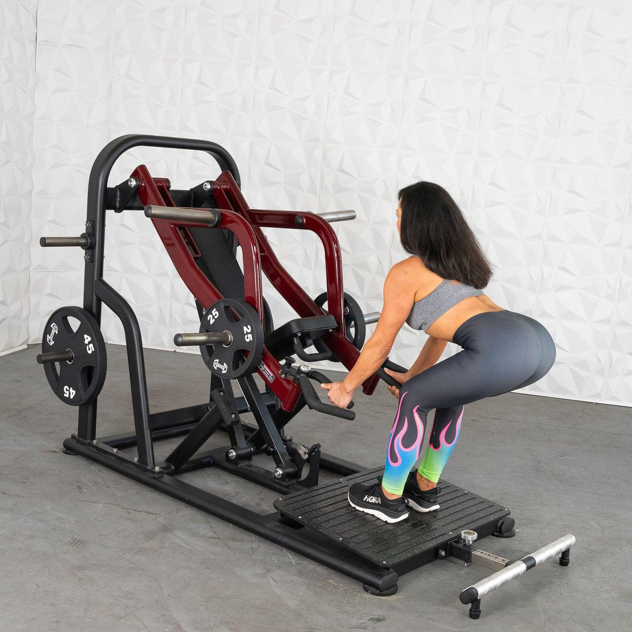 Woman using a red and black chest-supported row machine with weights.