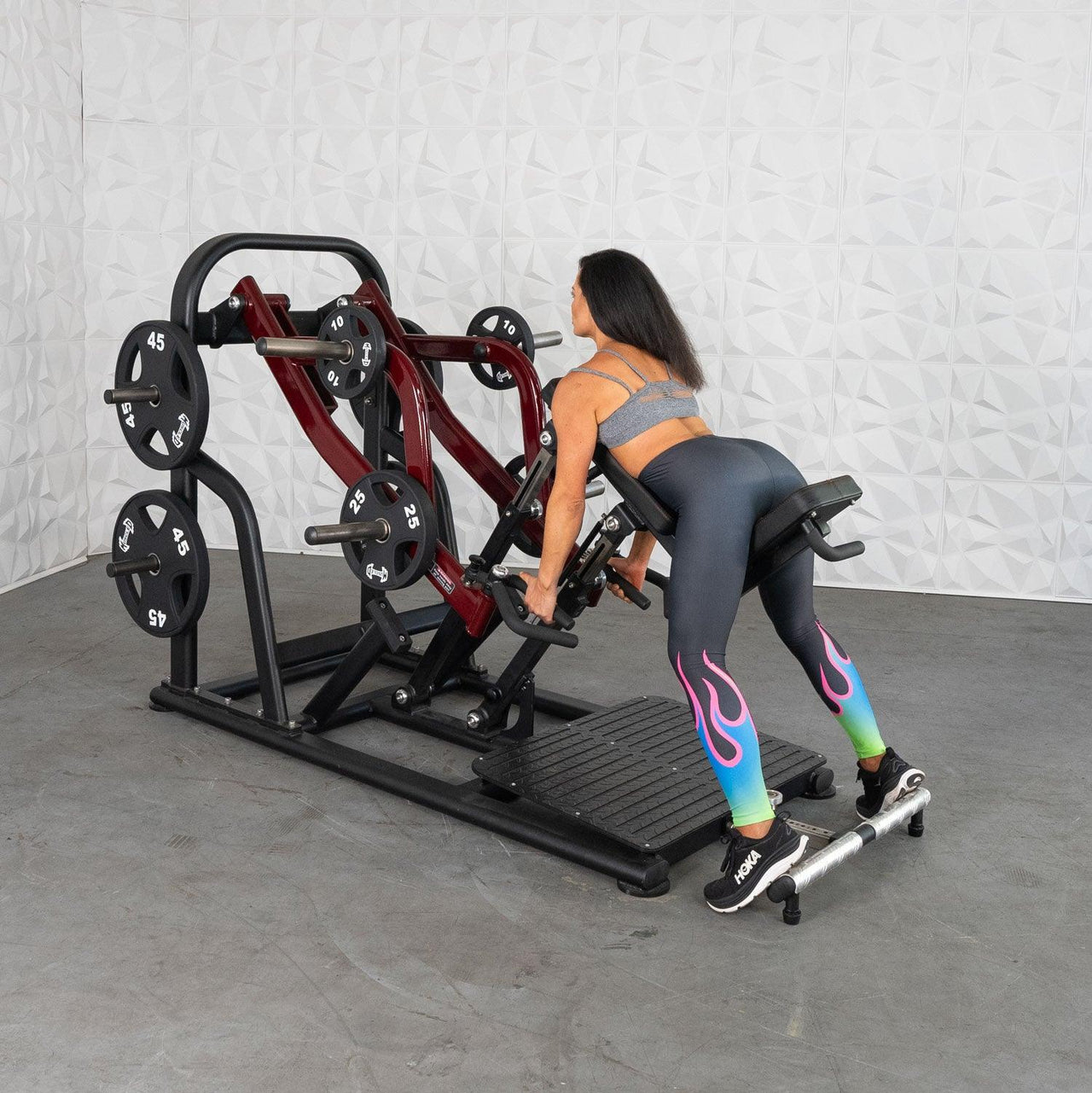 Woman using a chest-supported plate-loaded row machine with weight plates.
