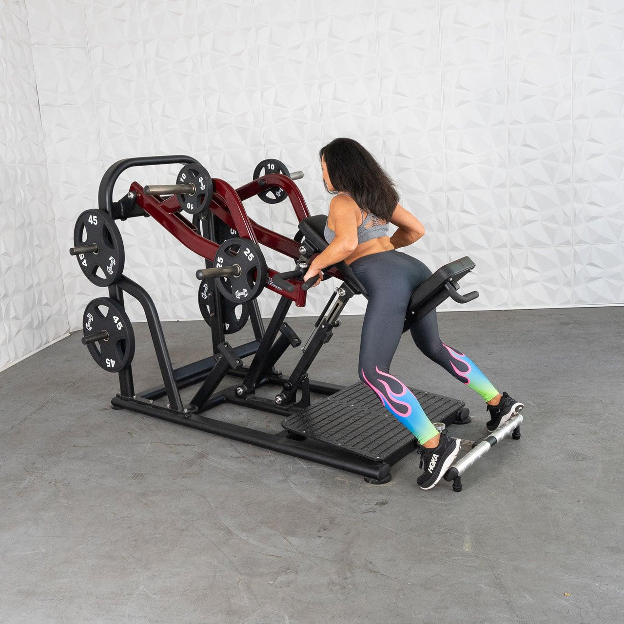 Woman using a chest-supported plate-loaded row machine with red arms and black weight plates.
