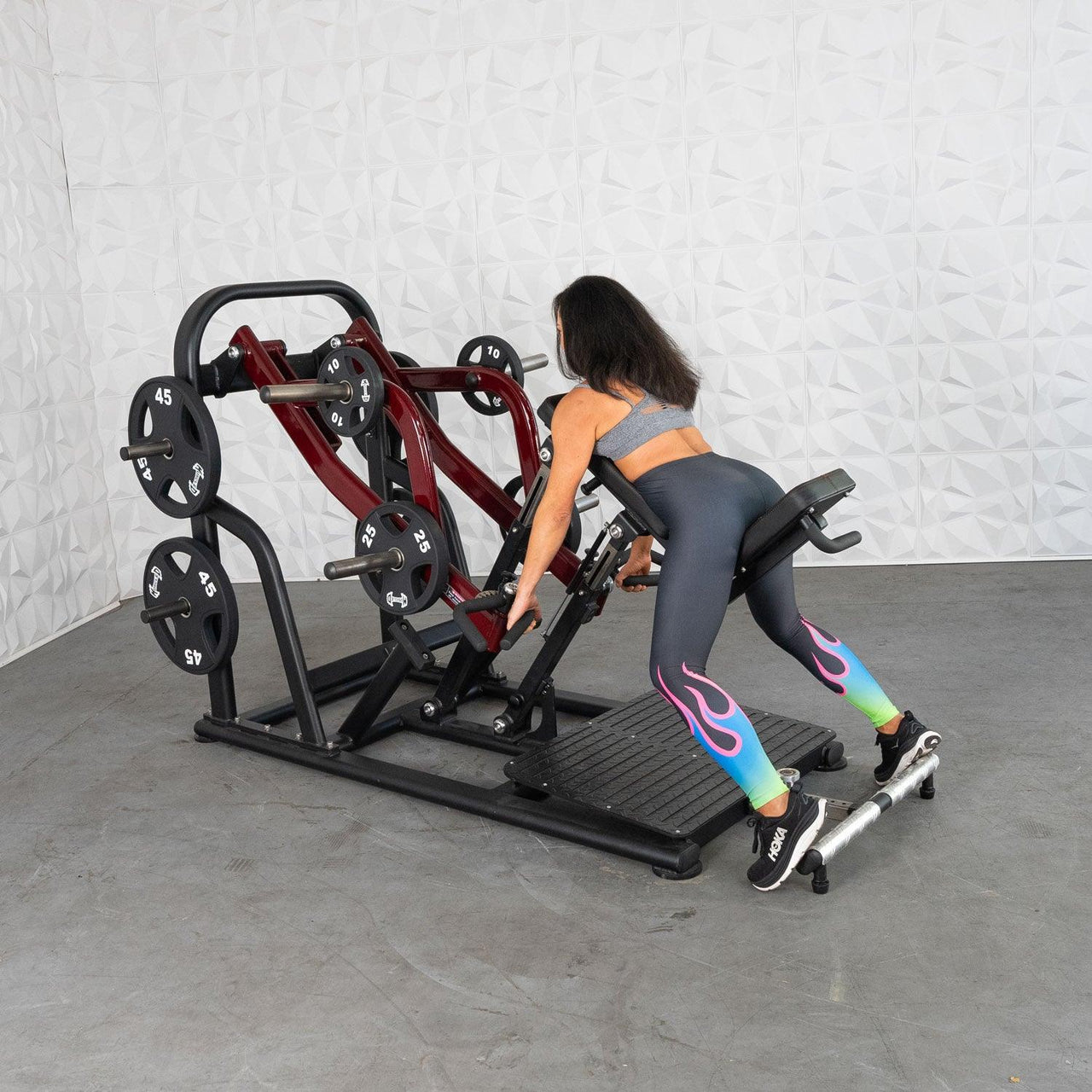 Woman using a red and black chest-supported row machine with plate weights in a gym.