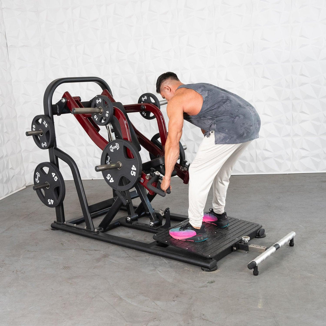Man using a black and red plate-loaded chest-supported row machine with 45lb and 10lb plates.