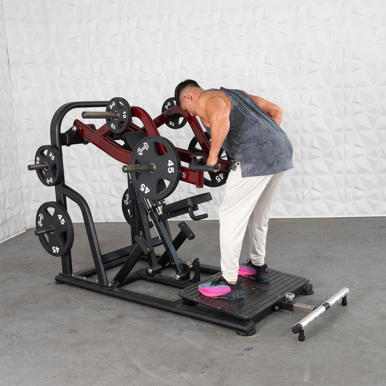 Man using a red and black plate-loaded chest-supported row machine with 45lb plates.