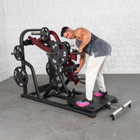 Thumbnail for Man adjusting a black and red plate-loaded chest-supported row machine with 45lb and 10lb weight plates.