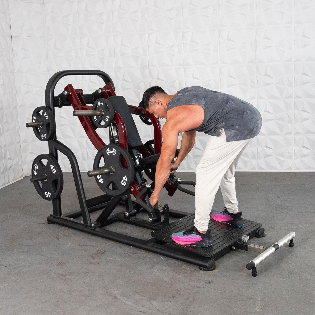 Man adjusting a red and black plate-loaded chest-supported row machine with 45lb weights.