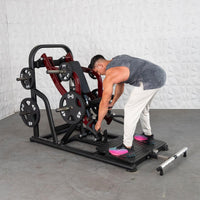 Thumbnail for Man adjusting a red and black plate-loaded chest-supported row machine with 45lb weights.