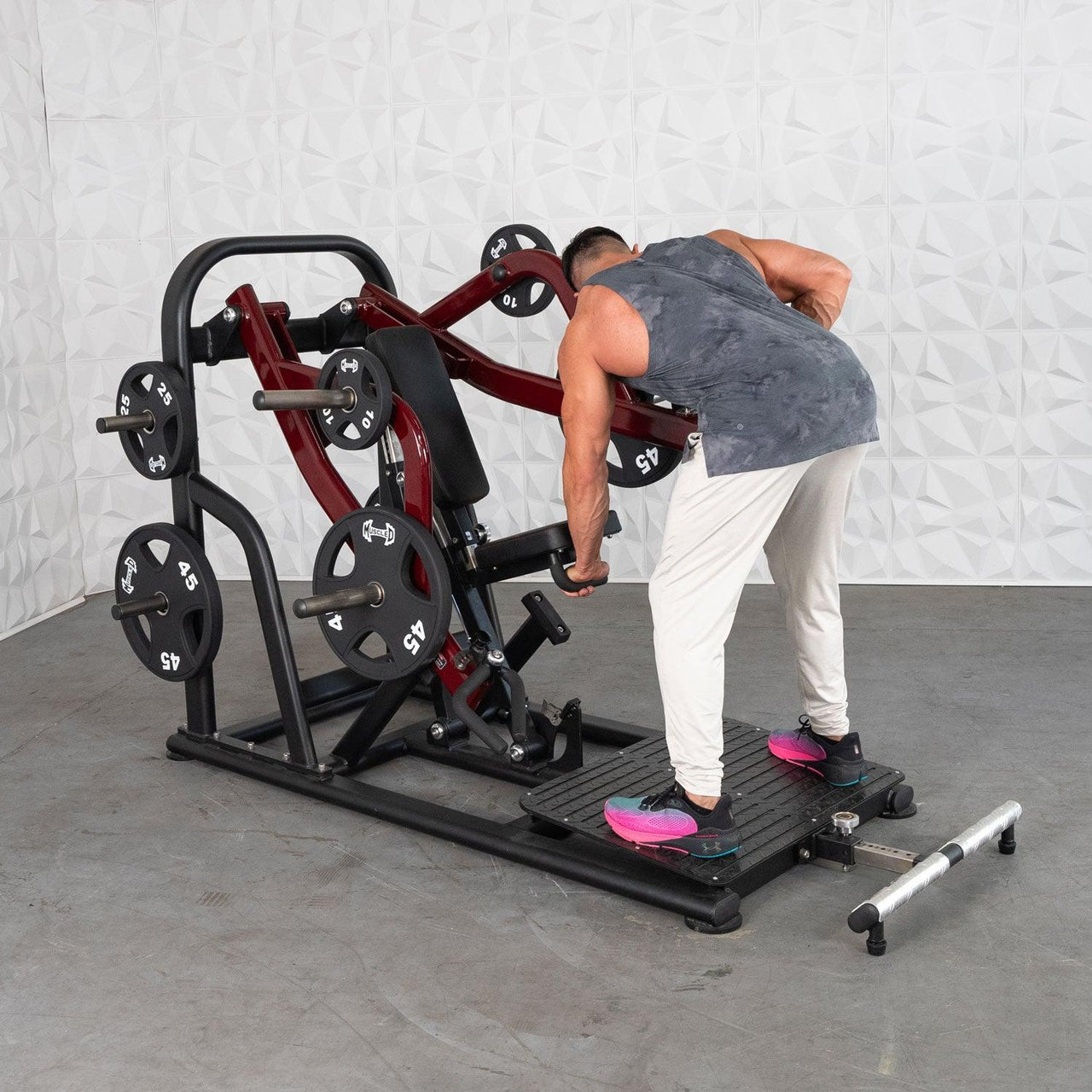 Man using a red and black plate-loaded chest-supported row machine in a gym.